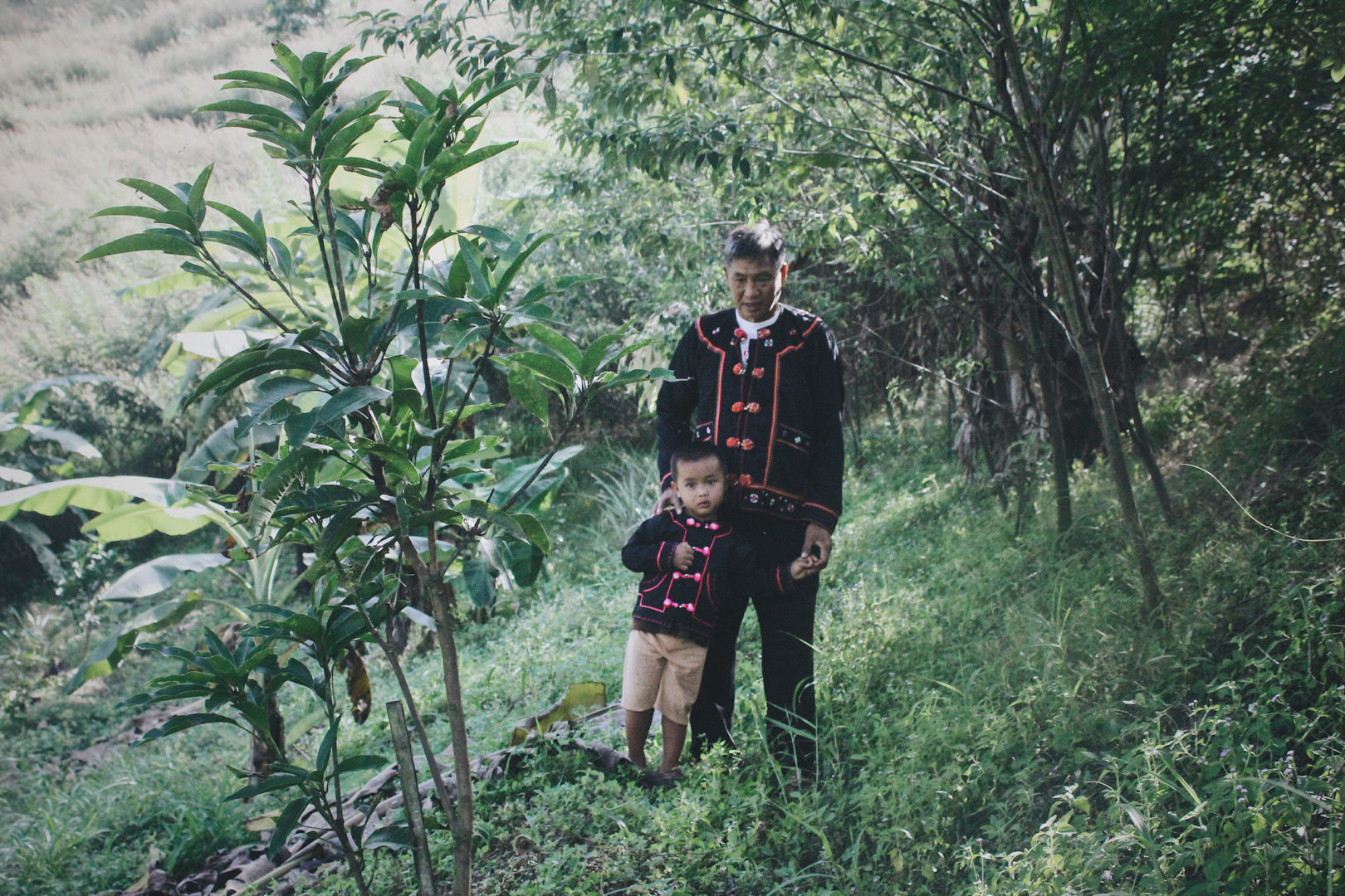 Chagga walks through a farm field with his grandson.